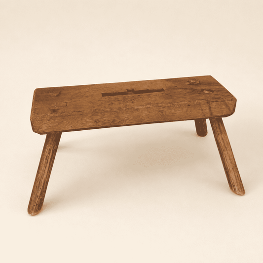 Front view of antique primitive plank foot stool with carved handhold