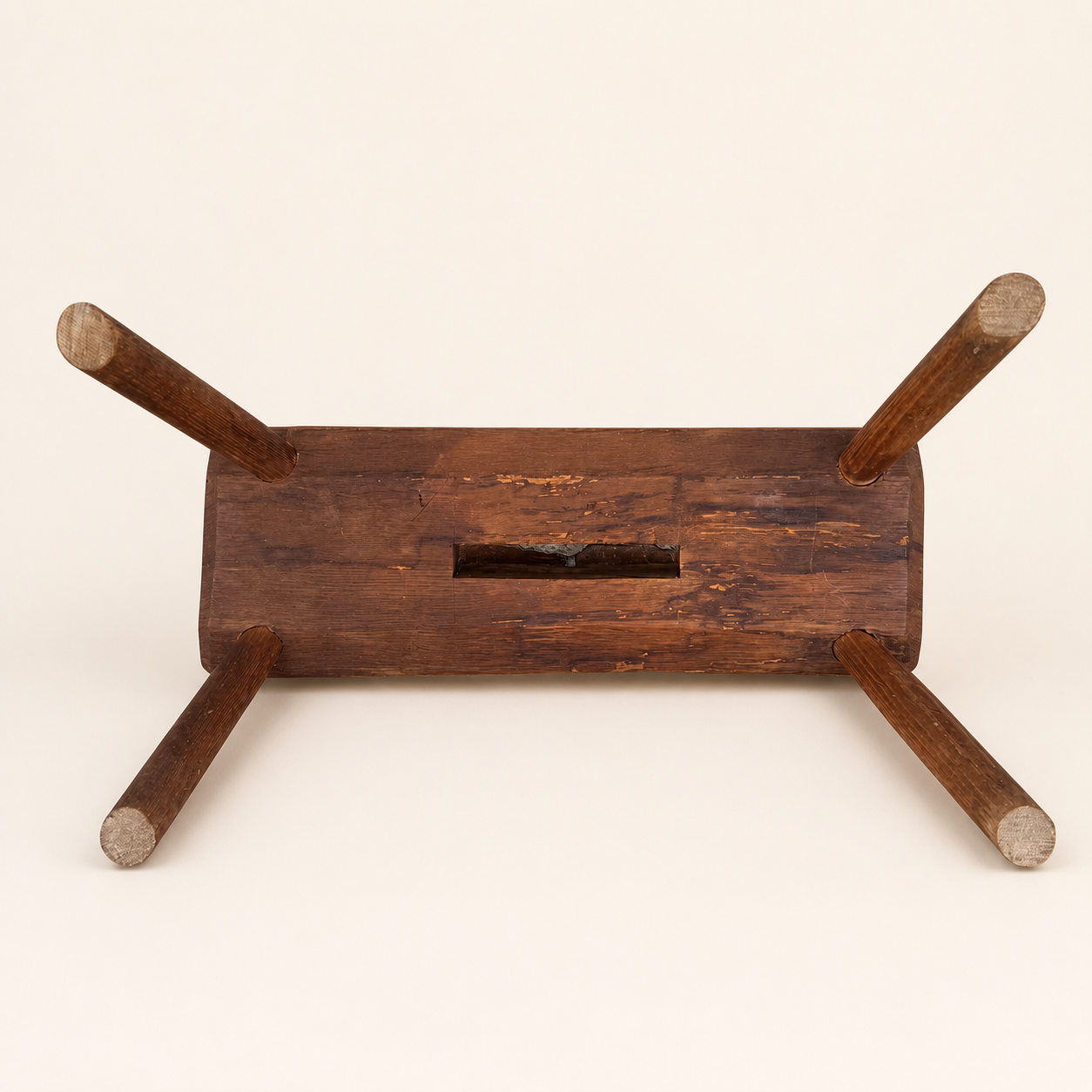 Underside of primitive foot stool showing leg tenons and handhold slot