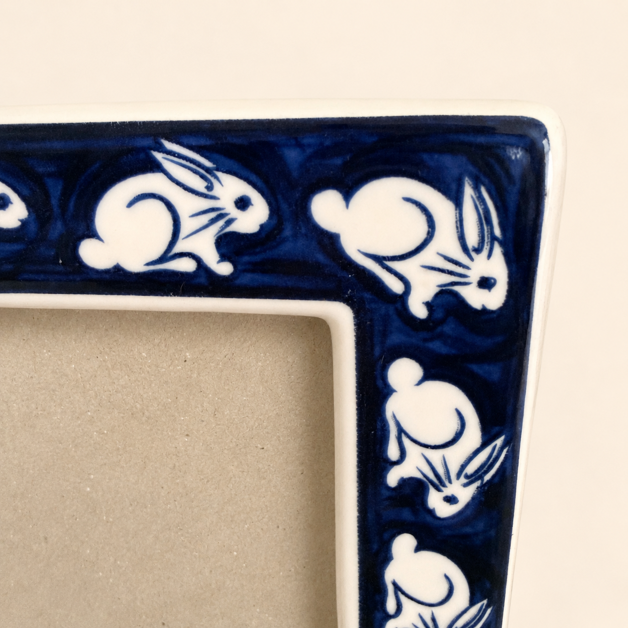 Close-up of white rabbits on cobalt blue border of ceramic photo frame