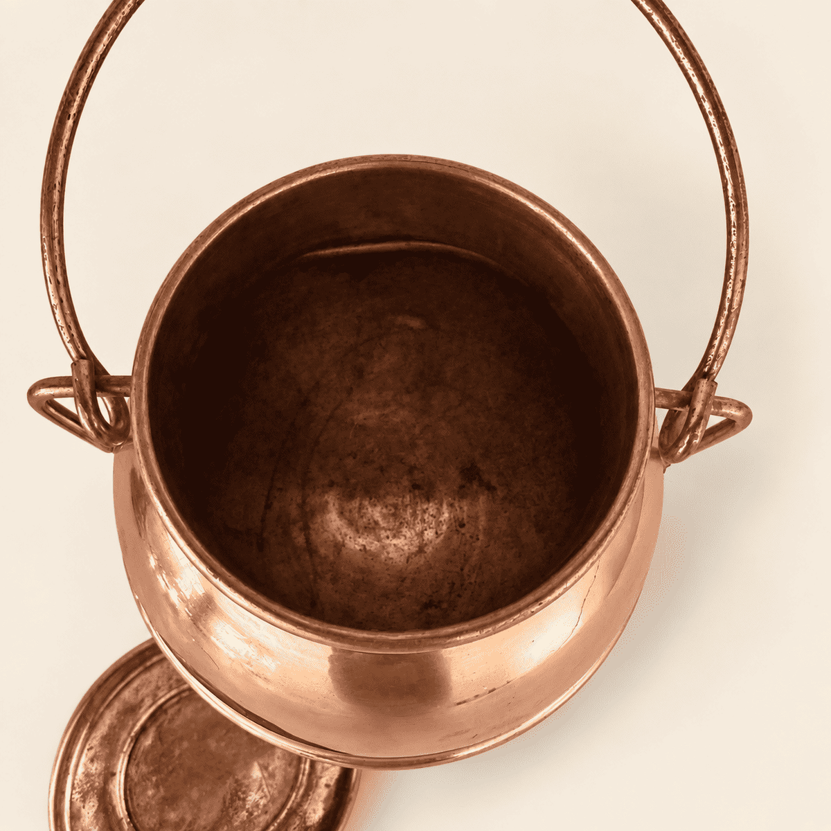 Looking down into the open copper cauldron, lid beside it