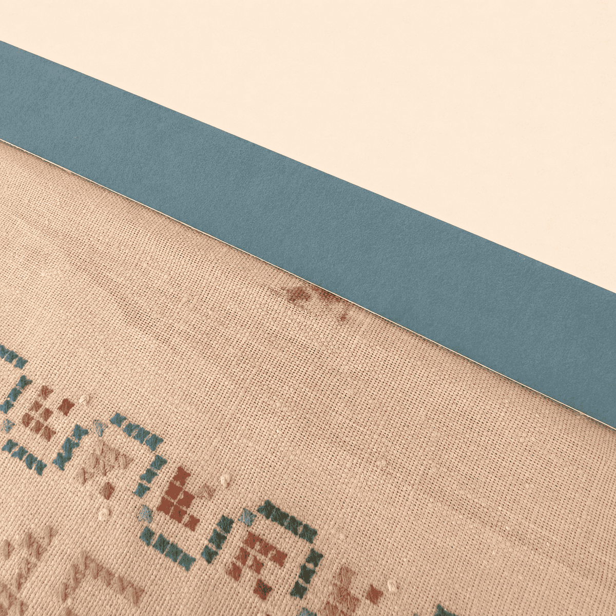 Detail of small brown stain on sampler linen