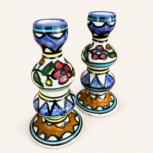 Angled view of a pair of hand-painted folk ceramic candlesticks
