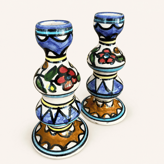 Angled view of a pair of hand-painted folk ceramic candlesticks
