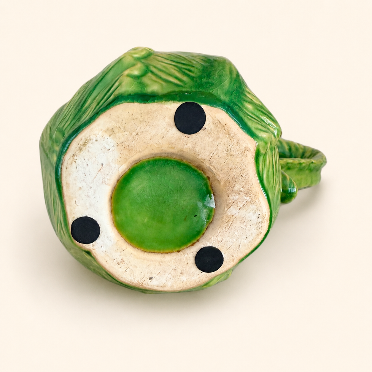 Unglazed base of green majolica cabbage leaf pitcher with felt pads