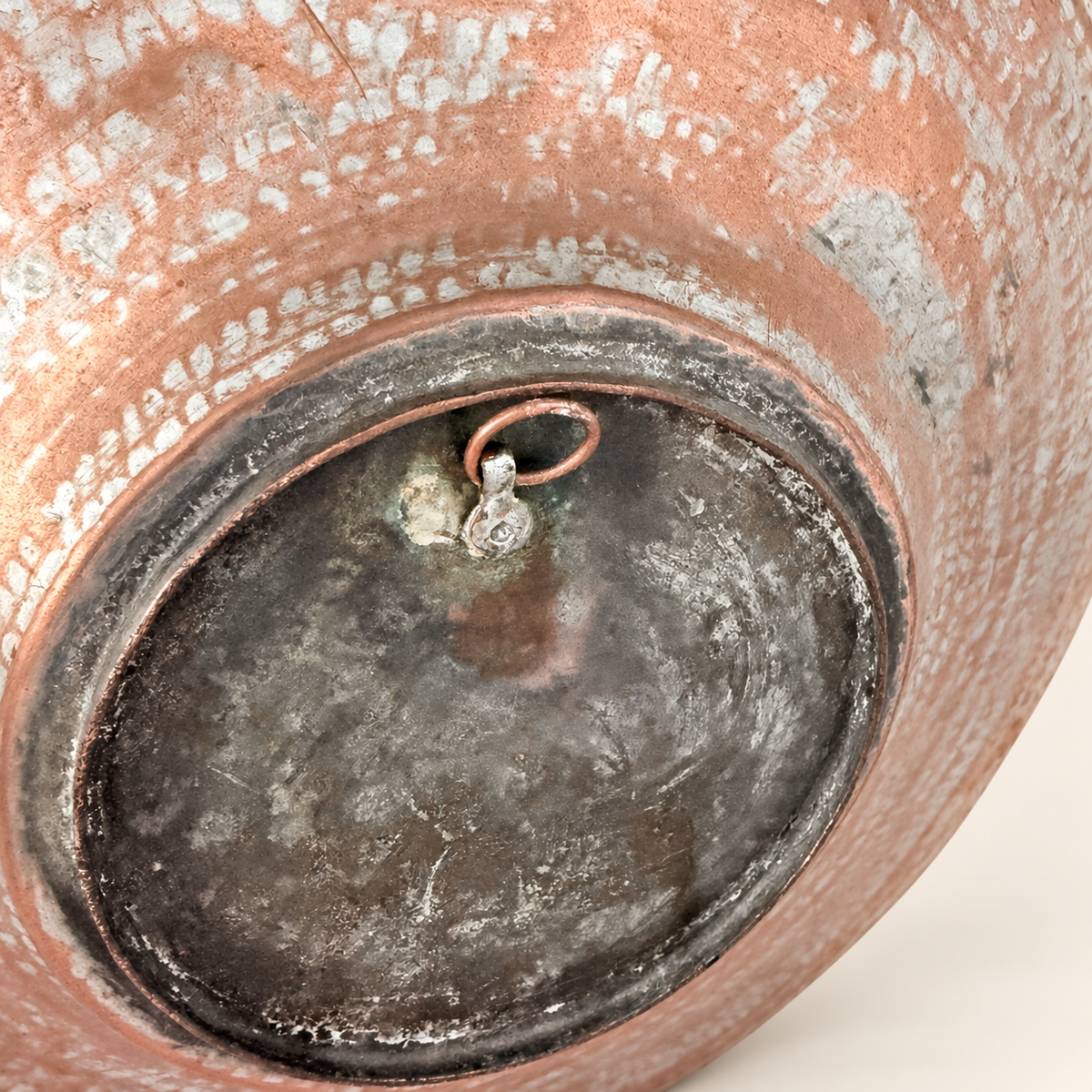Close detail of the copper hanging ring riveted to the raised center on the back of the charger