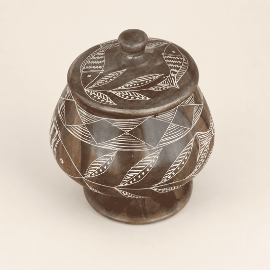 Top view of soapstone jar lid with etched fish and leaves