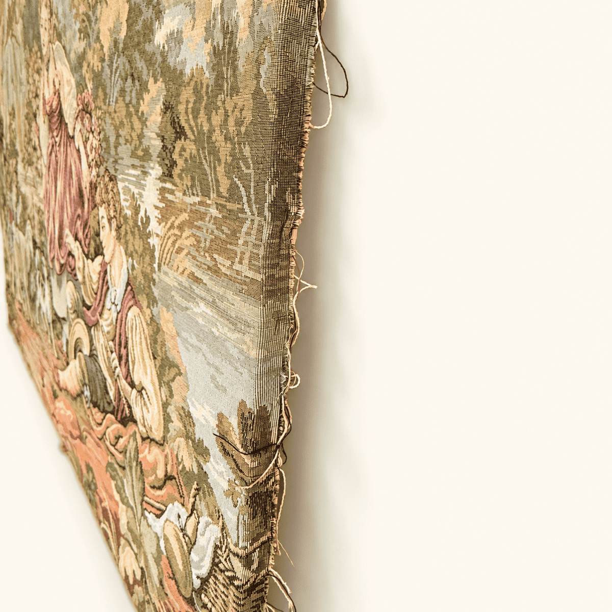 Raw unfinished edge of a vintage jacquard tapestry with loose threads