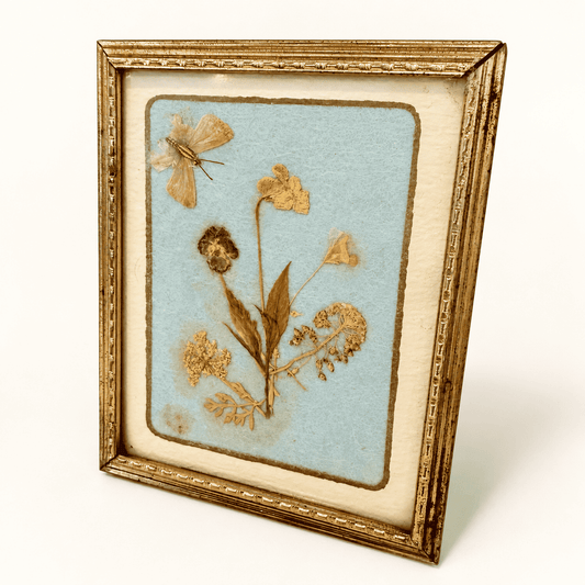 Angled view of small pressed flower frame on blue paper, photo 2 of 4