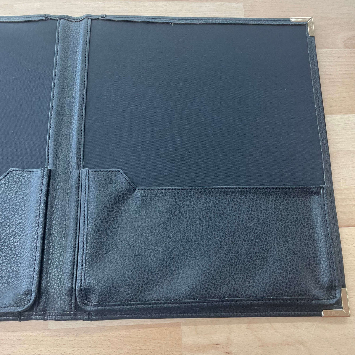 Black leather portfolio — open to interior pockets and notepad slot