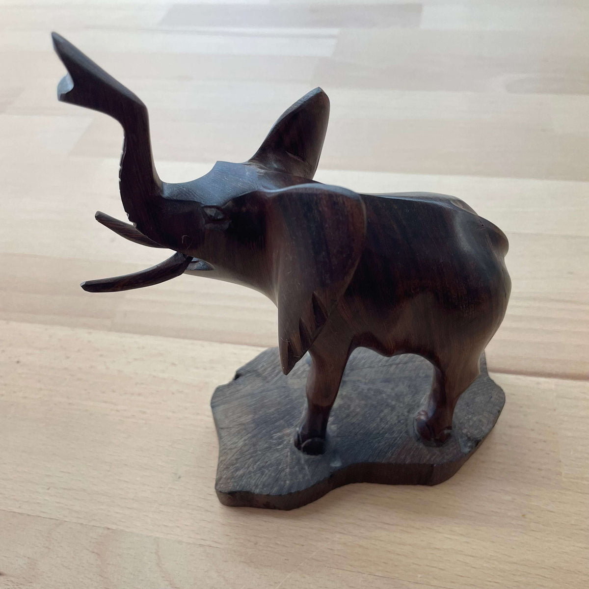 Carved wooden elephant — side profile with trunk up