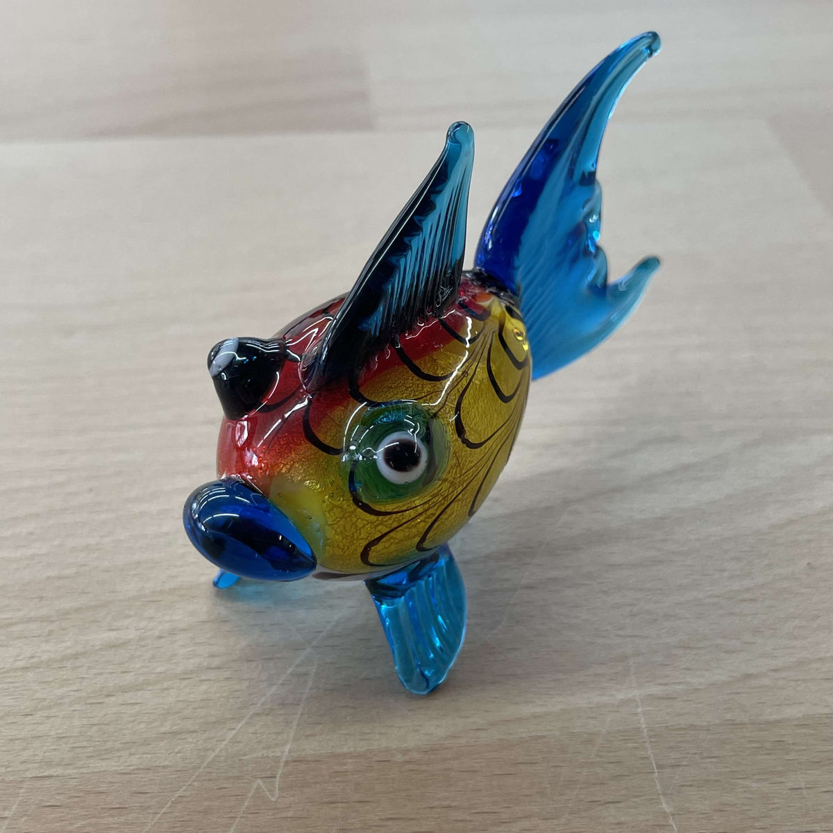Art glass rainbow fish figurine with a red and yellow body and tall blue fins