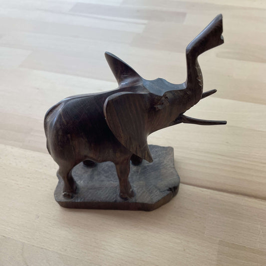 Hand-carved dark hardwood elephant figurine with trunk raised, on a natural wood base