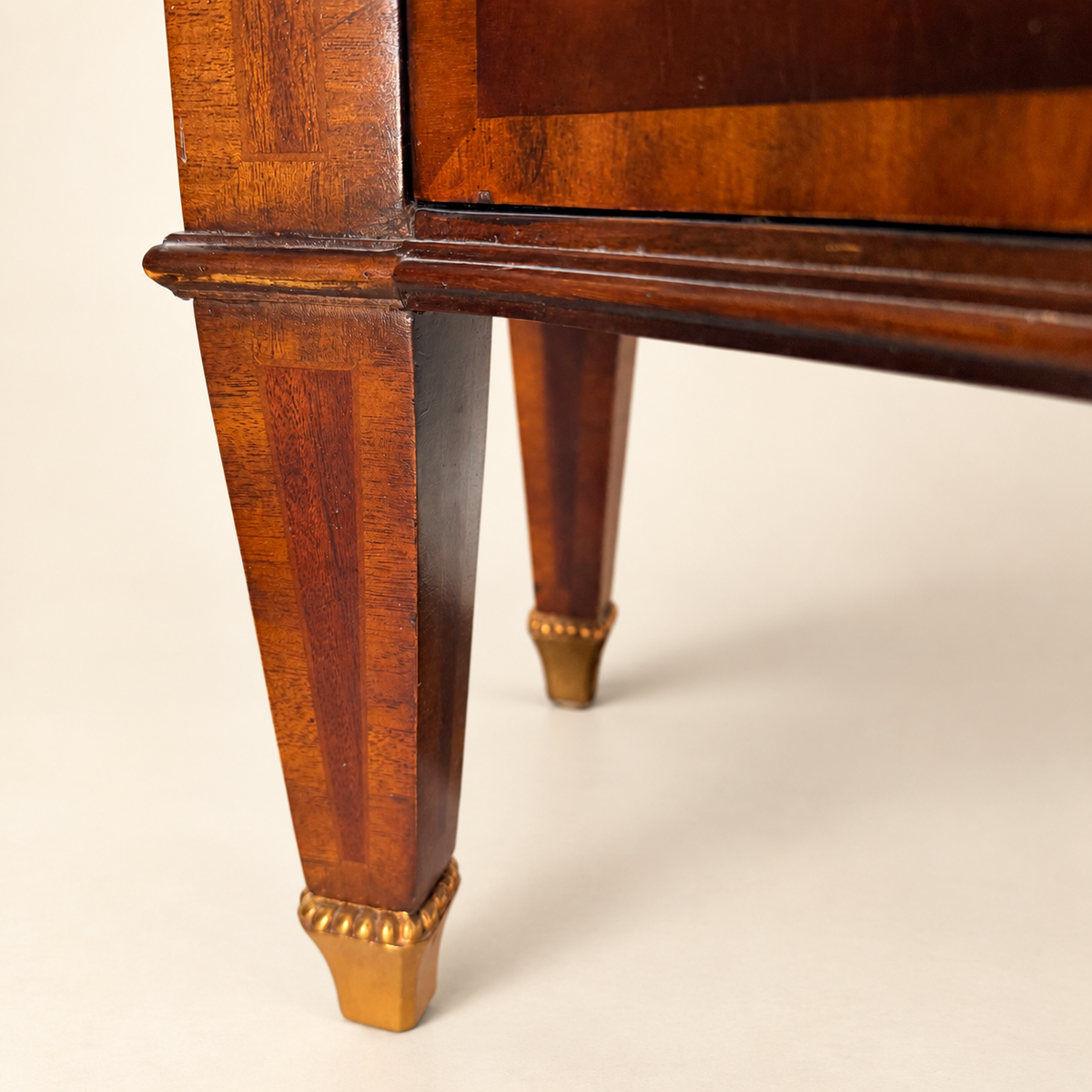 Tapered inlaid legs and shaped apron of the flame mahogany commode