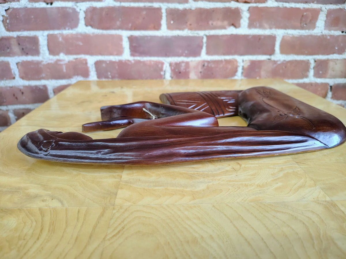 Carved wood wall art — full panel against a brick wall