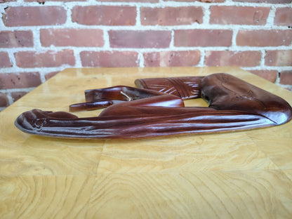 Carved wood wall art — full panel against a brick wall