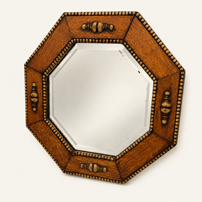 Jacobean-revival oak octagonal mirror shown at an angle, showing the faceted beveled glass and carved wood frame