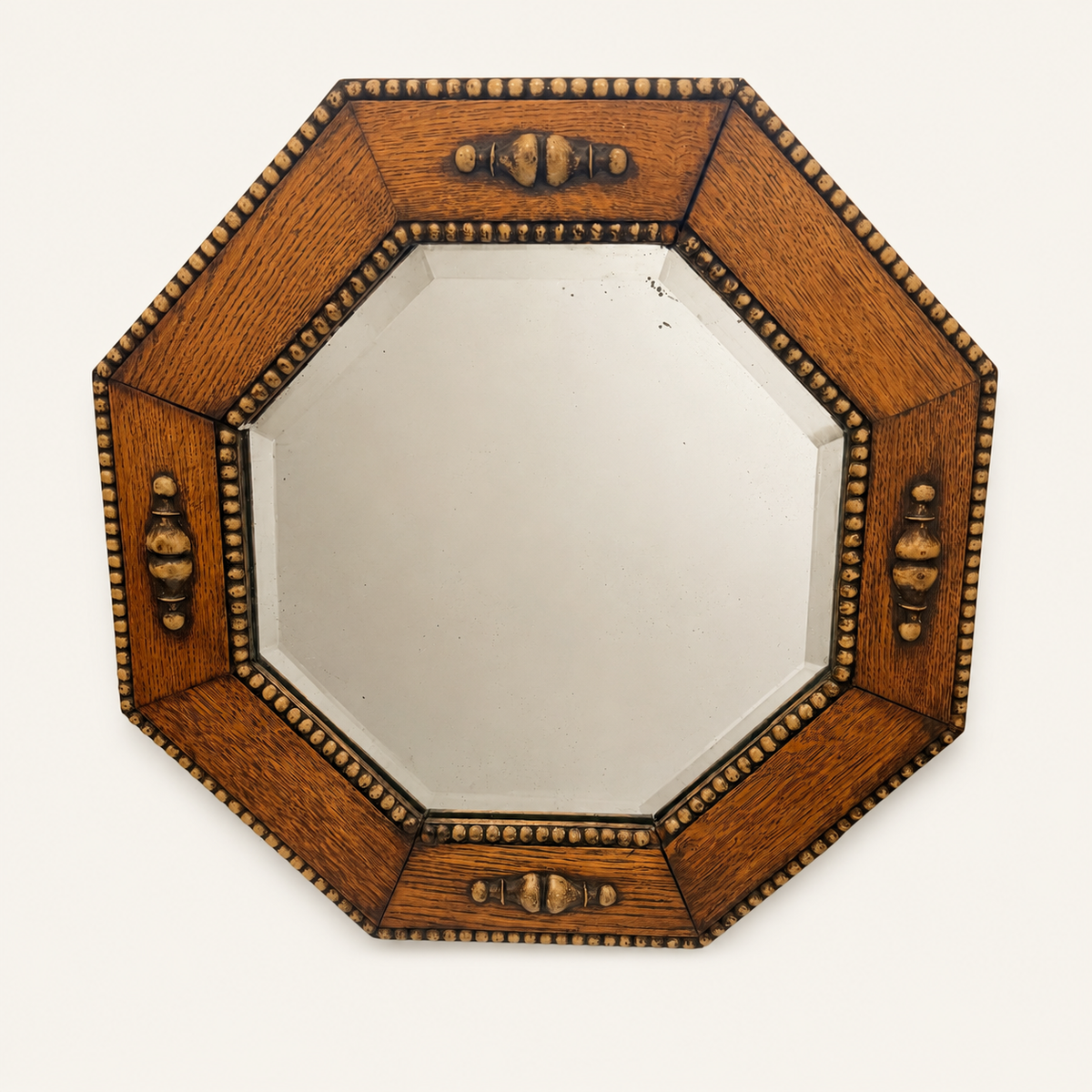 Straight-on view of the octagonal oak-framed beveled wall mirror with turned finials at four points