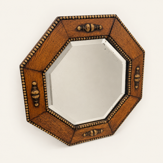 Antique 1930s English oak octagonal wall mirror with beveled plate, beaded gadroon border and turned urn finials, angled front view