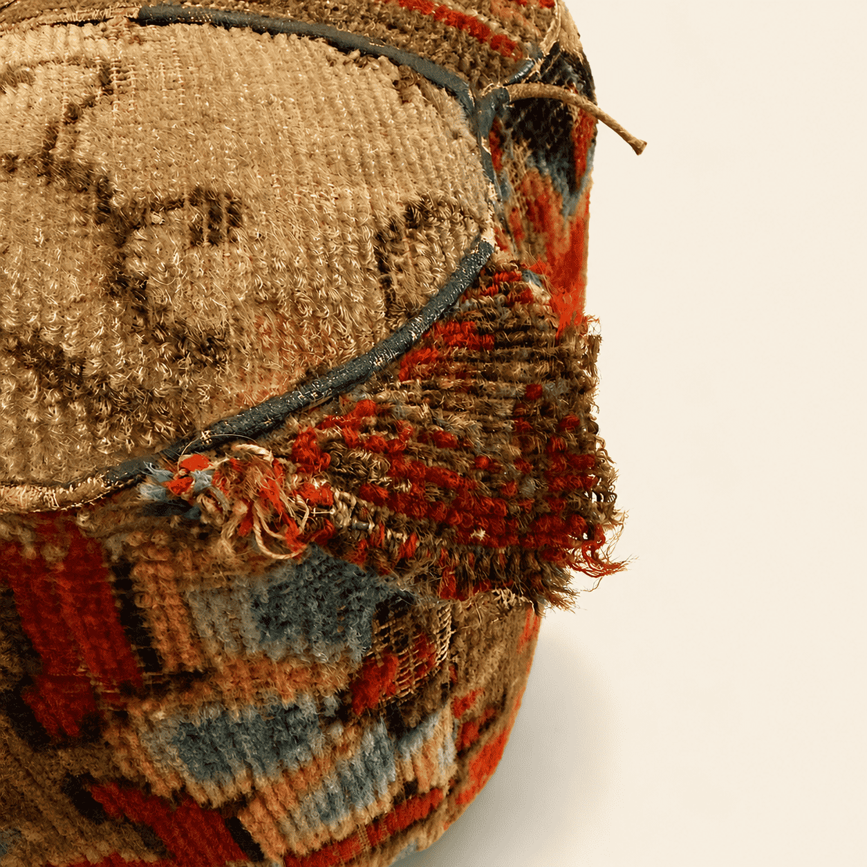 Original woven pull tab at the top edge of the antique carpet footstool