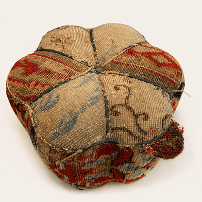 Top of the antique Oriental carpet footstool showing the lobed six-panel rug pattern