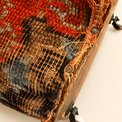 Antique carpet footstool showing honest age and worn pile