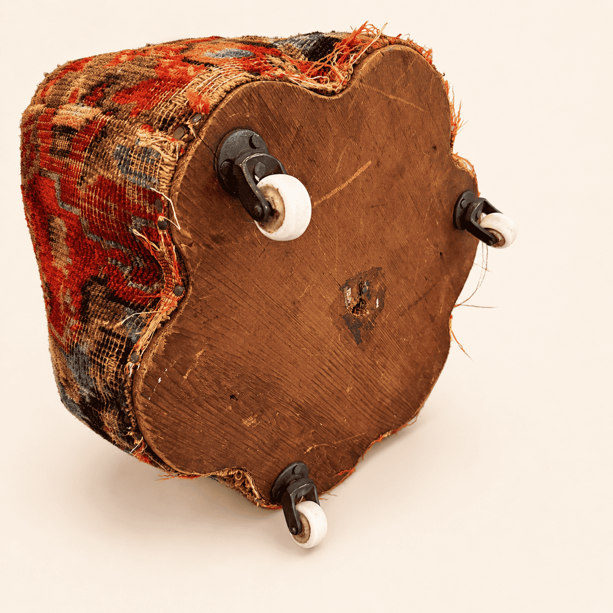 Underside of the antique footstool showing the wood base and porcelain casters