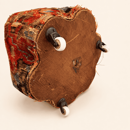 Underside of the antique footstool showing the wood base and porcelain casters
