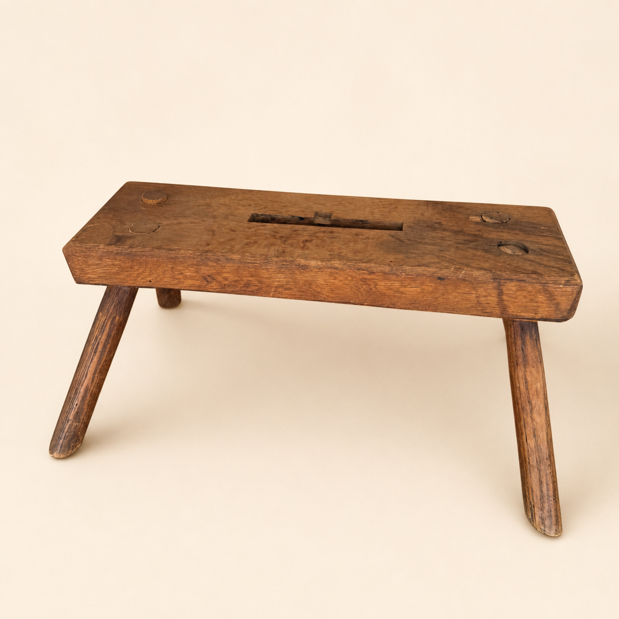 Three-quarter view of antique primitive wooden foot stool with worn patina