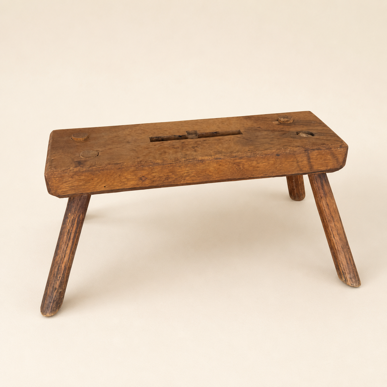 Front view of antique primitive plank foot stool with carved handhold
