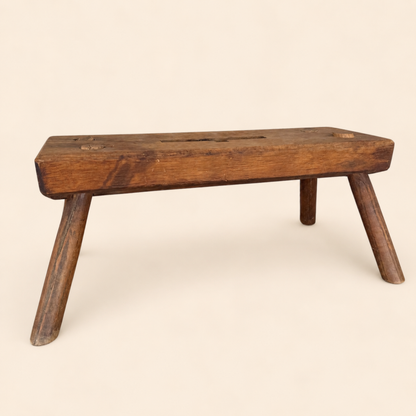Side view of antique primitive plank stool showing thick top and splayed legs