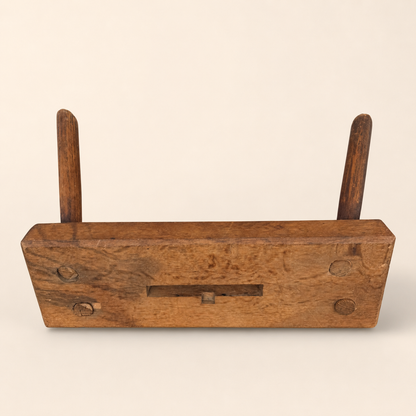 Top-angled view of primitive wooden foot stool showing pegs and carved handhold