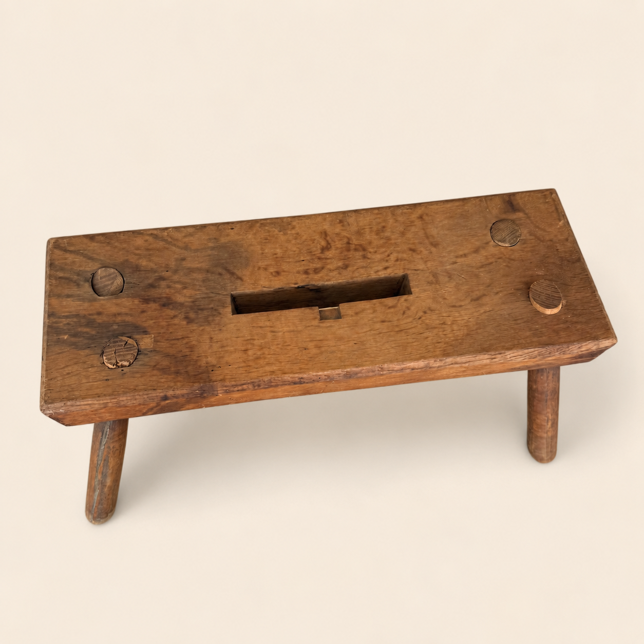 Top-down view of primitive stool plank showing pegged joints and handhold slot
