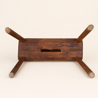 Underside of primitive foot stool showing leg tenons and handhold slot