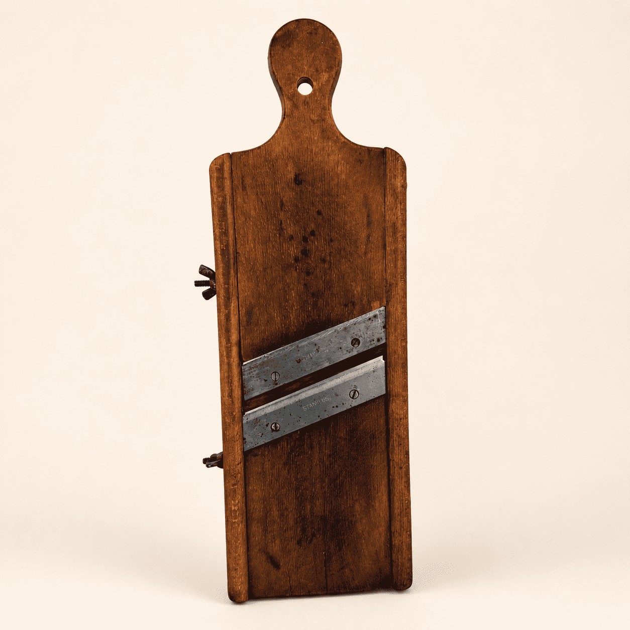 Antique wooden cabbage kraut slicer with two angled blades and hanging hole, front view