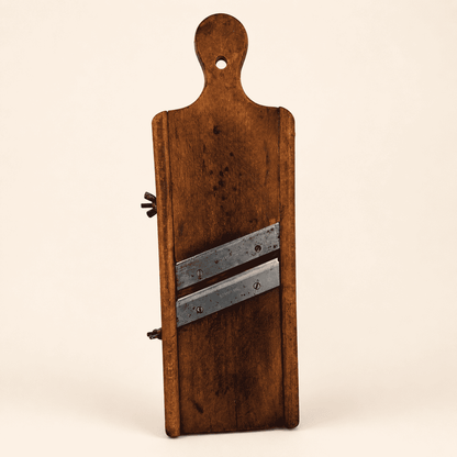 Antique wooden cabbage kraut slicer with two angled blades and hanging hole, front view