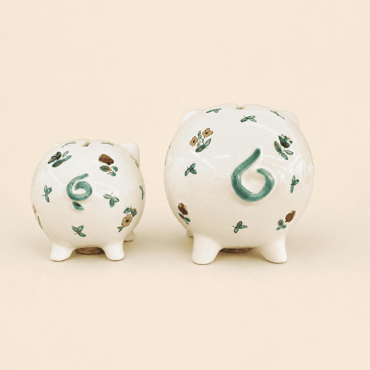 Two small piggy banks from behind showing green curly tails and coin slots