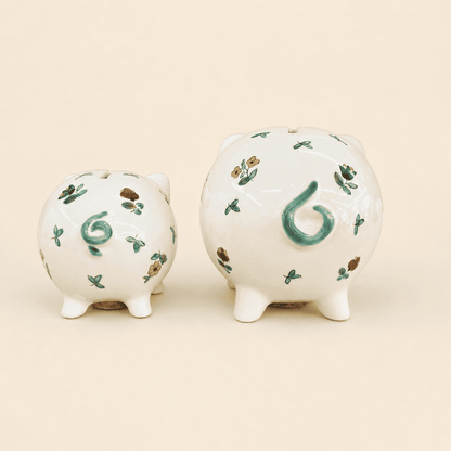 Two small piggy banks from behind showing green curly tails and coin slots