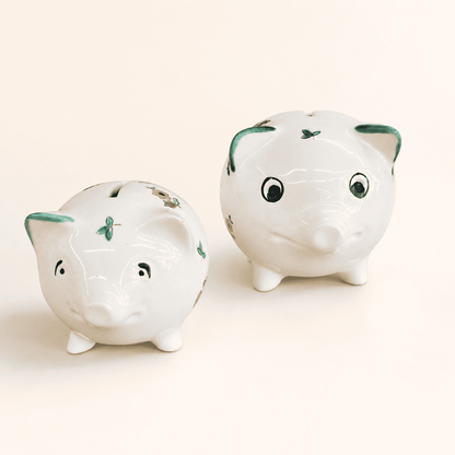 Two small hand-painted piggy banks showing faces and scattered-flower pattern