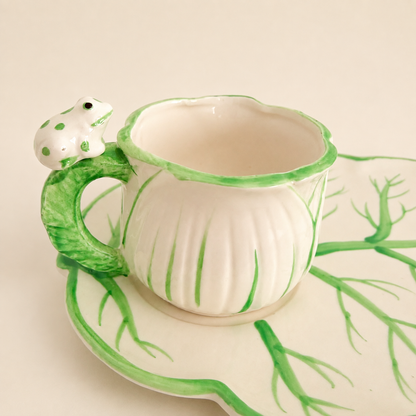 Detail of a cup with a small frog perched on the leaf handle