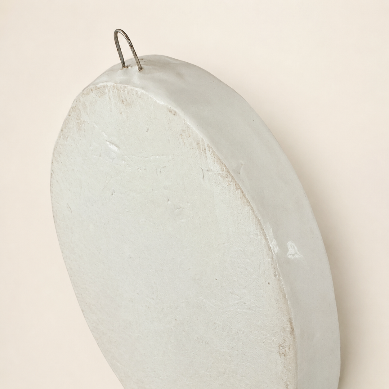 Angled back view of ceramic floral plaque with hanger