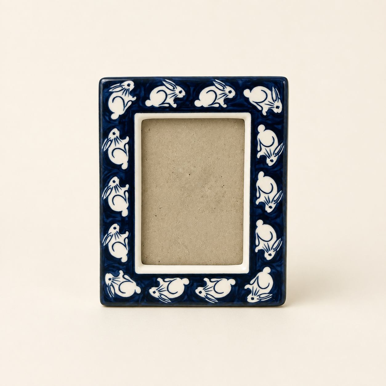 Angled view of blue and white bunny ceramic photo frame with easel back