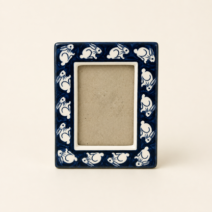 Angled view of blue and white bunny ceramic photo frame with easel back