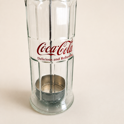 Detail of the red Coca-Cola "Delicious and Refreshing" logo on the glass dispenser