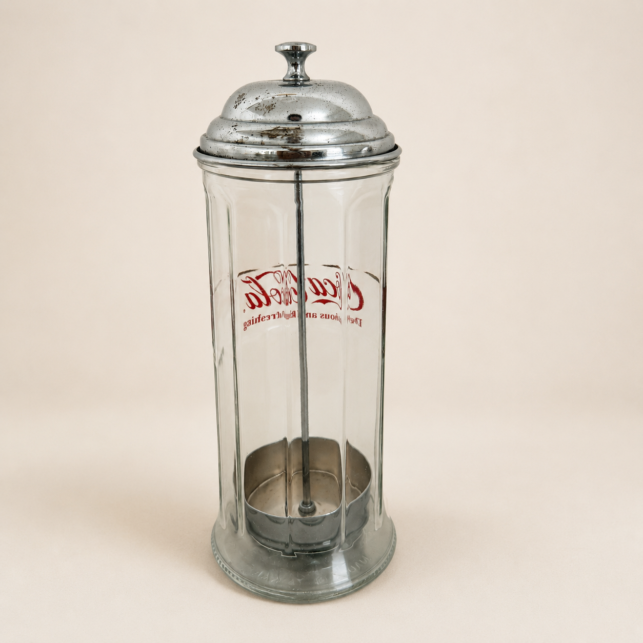 Back of the Coca-Cola straw dispenser showing reversed logo through the glass