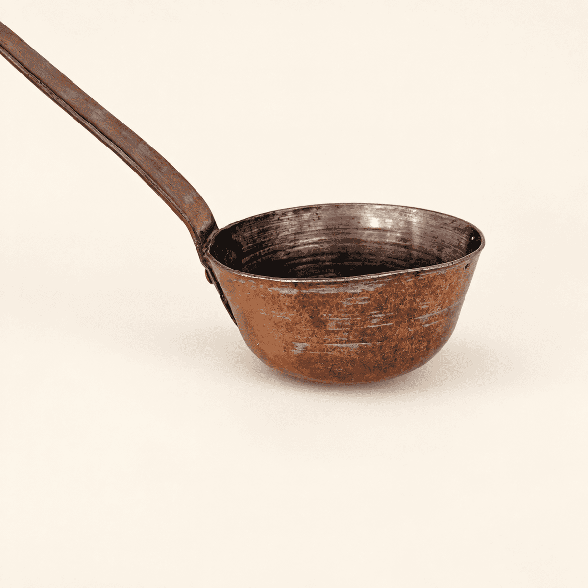 Copper dipper bowl with the long handle angled up, worn tin interior