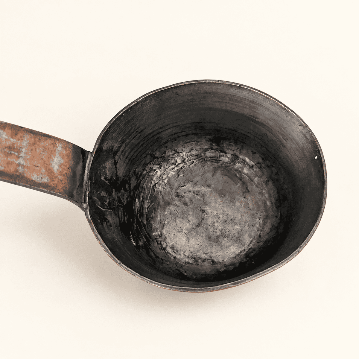 Looking down into the tin-lined bowl of the dipper, handle riveted at the rim