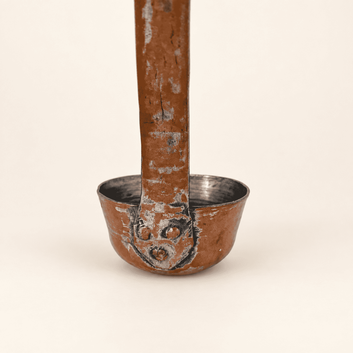 Copper rivets fastening the flat forged handle to the bowl of the dipper