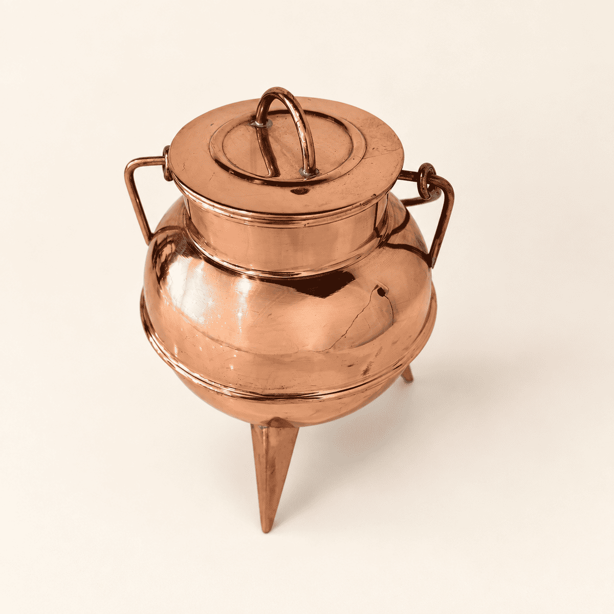 Copper cauldron viewed from above at an angle, spike feet and copper bail