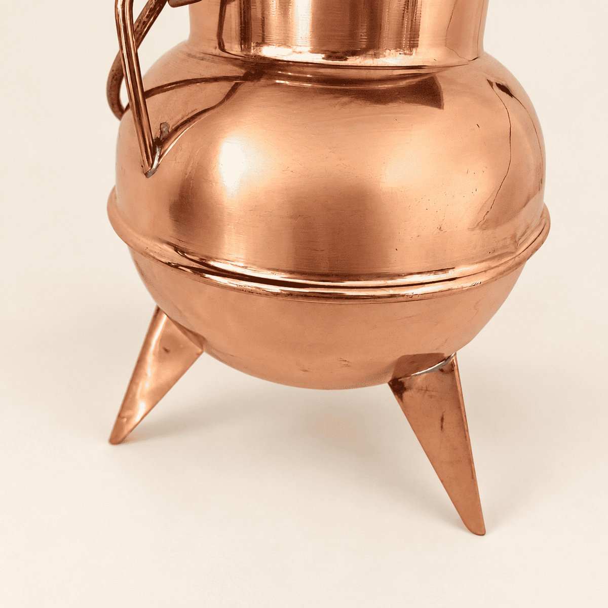 Polished copper belly and tapered spike feet of the cauldron