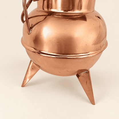 Polished copper belly and tapered spike feet of the cauldron